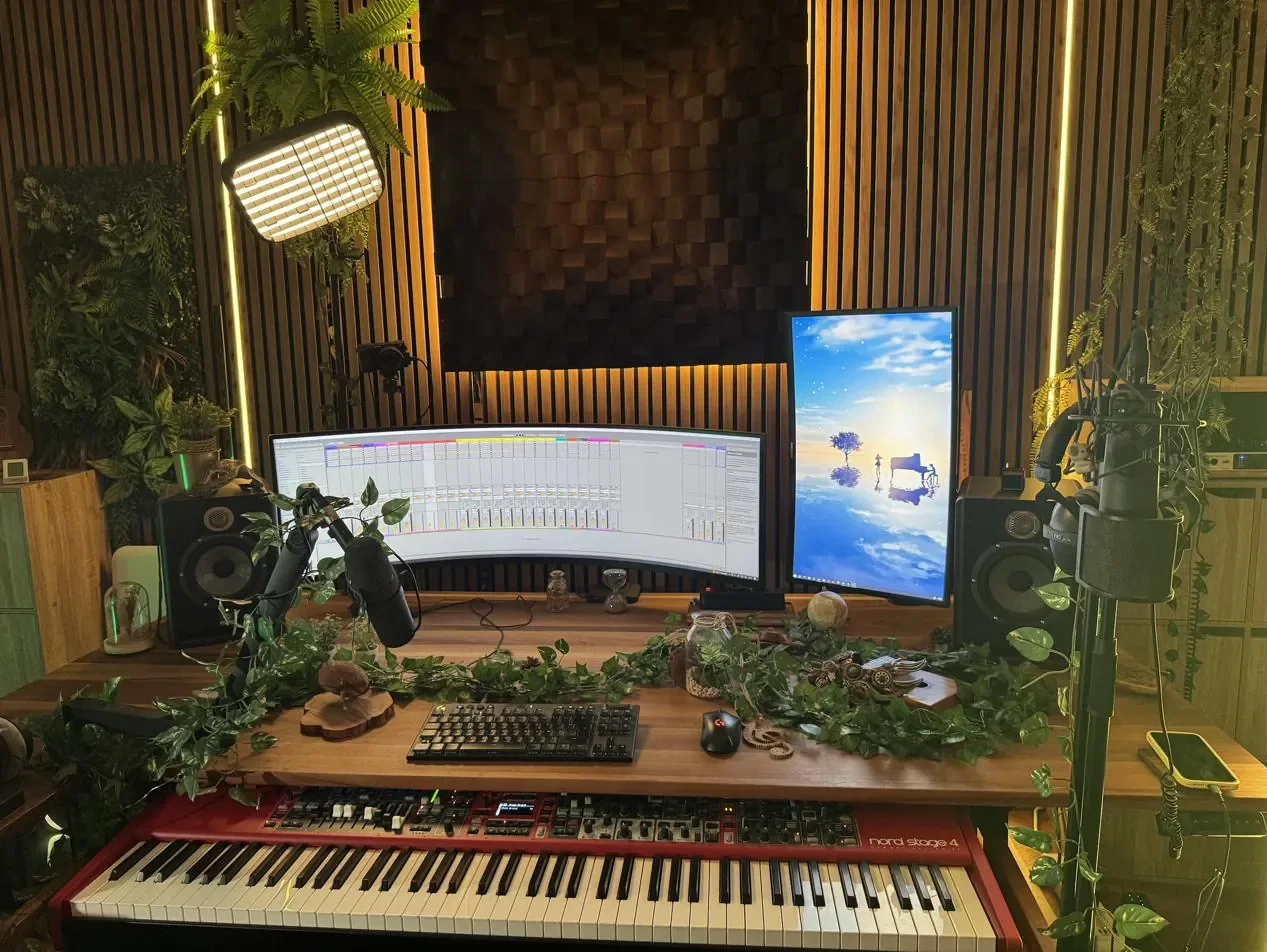 Le studio d'Elemental XII : mur de tasseaux éclairé de lumière ambrée, diffuseur acoustique, plantes, écrans, micro et Nord Stage 4 rouge.