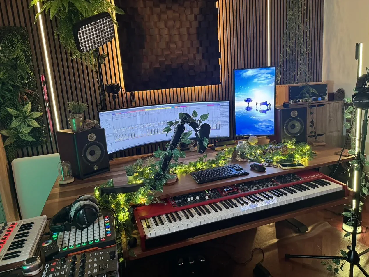 Le studio le soir : guirlande lumineuse sur le bureau, Nord Stage 4, écrans et mur de tasseaux.